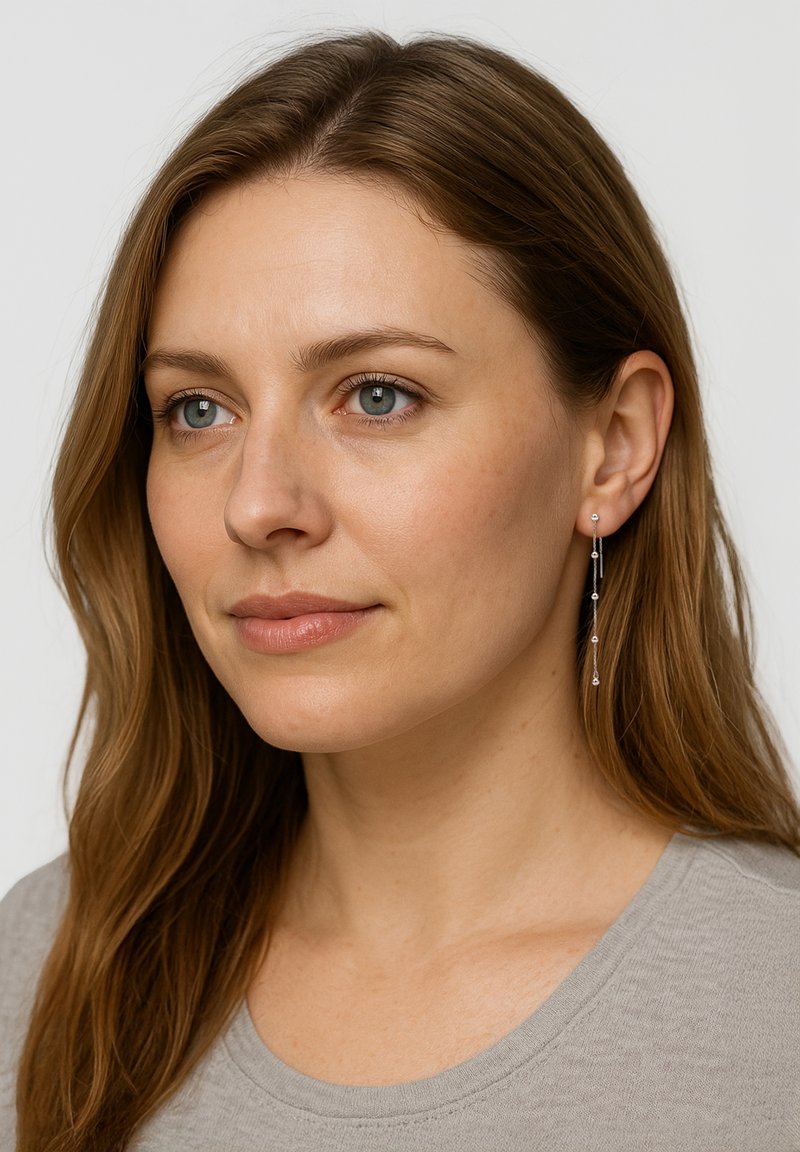 Boucles d'oreilles argentées en forme de goutte avec des chaînes verticales ornées de petites perles rondes de tailles variées. Design simple, formes fines et allongées.