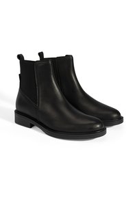 Bottines Chelsea en cuir noir avec des panneaux élastiques sur les côtés, des semelles en caoutchouc plates et des tirettes à l'arrière pour un enfilage facile. Finition lisse et design élégant.
