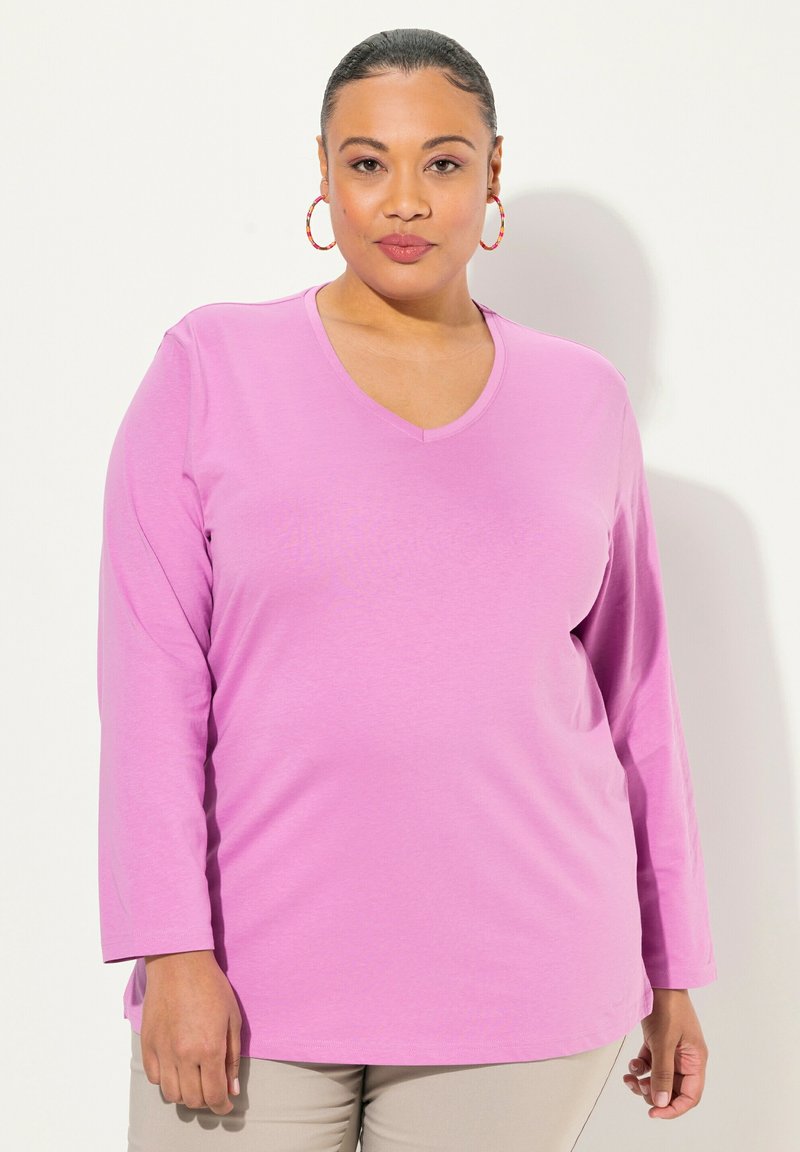 Top a maniche lunghe e scollo a V in un rosa uniforme, realizzato in tessuto morbido. Presenta una vestibilità rilassata con orlo leggermente arrotondato.