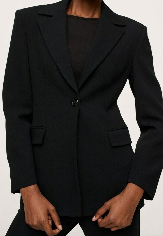 Blazer noir sur mesure avec un bouton, de larges revers et des poches à rabat, porté sur un haut noir.