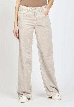 Beige corduroy wide-leg pants with a soft texture, featuring a front button closure and pockets. Worn with white sneakers.