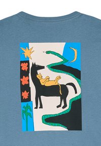 Blå t-shirt med et farverigt grafisk motiv: en sort hest med en gul kat, omkranset af en grøn slange, stjerner og blomster.