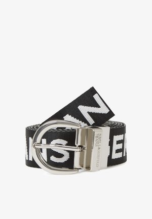 Mustmustri vöö suure valge tekstiga, hõbedase tooni metallist pandla ja reguleeritava pikkusega, mis näitab vastupidavat kudumist.