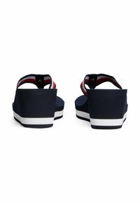 Sandali wedge navy con suola bianca, dotati di cinturini a righe rosse e bianche. Il materiale sembra morbido con una finitura liscia. Vista posteriore mostrata.