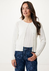 Biała kardigan o prążkowanej strukturze z falistym dekoltem i zapięciem na guziki, w połączeniu z ciemnoniebieskimi dżinsami w kwiatowy wzór. Teksturowany i lekki design.