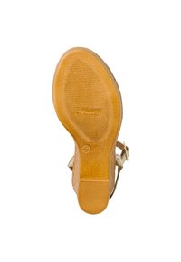 Brown rubber sole with textured grip, slightly curved shape, and embossed logo. Tan straps connect to a golden metal buckle for adjustment.