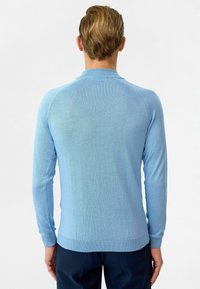 Lichtblauwe sweater met lange mouwen, ribgebreide manchetten en zoom, een gladde textuur en een eenvoudig ontwerp zonder zichtbare logo's of patronen.