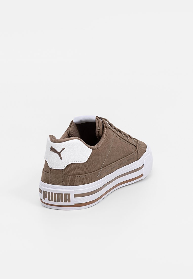 Zapatillas de lona marrones con acentos blancos, que presentan una superficie texturizada, parte frontal con cordones y detalles de marca en el talón. Suela de goma plana.