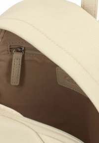 Interno di uno zaino in similpelle color crema con una piccola tasca con zip in tessuto beige coordinato. Texture liscia e design minimalista.