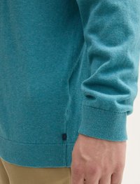 Turkusowy sweter z prążkowanymi mankietami i hemem, miękka dzianina, dopasowany krój. Mała etykieta blisko hemu.