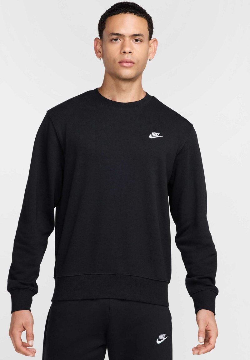 Felpa nera Nike con collo tondo, polsini e vita a costine. Presenta un piccolo logo bianco sul petto sinistro. Tessuto morbido in misto cotone.