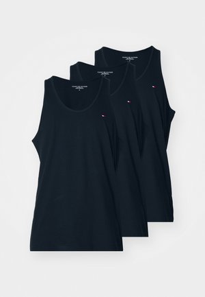 Drie zwarte mouwloze Tommy Hilfiger tanktops over elkaar heen gelegd, elk met een klein rood-wit-blauw logo op de borst.