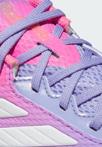 Nahaufnahme eines lila und pinken Sneakers mit lavendelfarbenen Schnürsenkeln und strukturierten Stoffdetails.