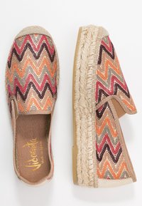 Ett par slip-on espadriller med flerfärgad zigzag-mönster och störböjda jutestrålsålar, fotograferade från ovan och sidan.