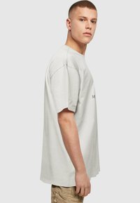 Camiseta de algodón gris claro con un corte relajado, manga corta y cuello redondo. Presenta un diseño minimalista sin patrones ni acentos visibles.