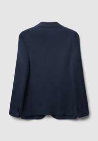 Blazer blu navy con tessuto testurizzato, revers a vista e due spacchi posteriori. Tre bottoni decorativi su ciascun polsino. Vista posteriore.