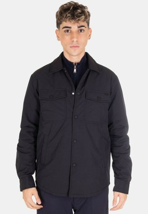 Giacca nera button-up con due tasche sul petto, colletto a punta e finitura in tessuto testurizzato. Presenta una chiusura frontale con bottoni a pressione.