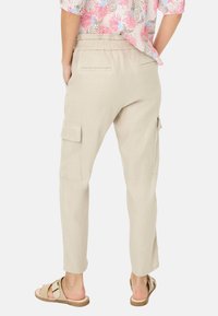 Beige Cargo-Hosen mit elastischem Bund, ausgestattet mit zwei Seitentaschen und zwei Gesäßtaschen, aus einem leichten, strukturierten Stoff.