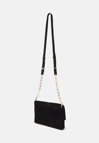 Borsa a tracolla in suede nero con una tracolla in catena dorata, forma rettangolare, superficie liscia e design minimalista.