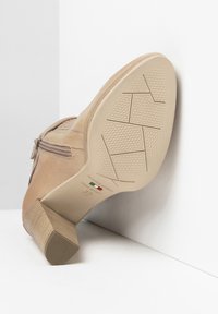 Stivale beige alla caviglia con tomaia in pelle testurizzata, cerniera laterale e tacco impilato. La suola presenta un motivo di grip in gomma.