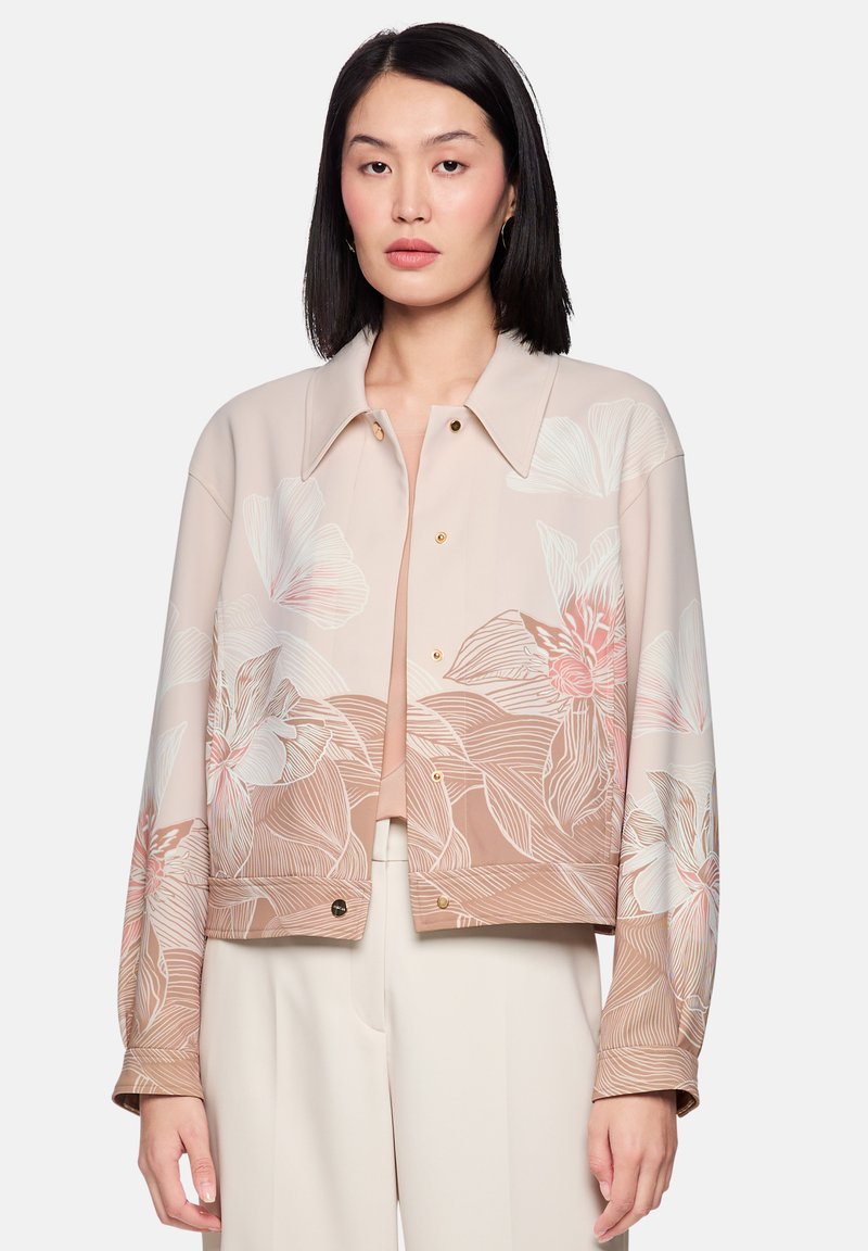 Cropped floral jacket in soft beige with gold snap buttons, featuring large pink and white flower designs on lightweight fabric.