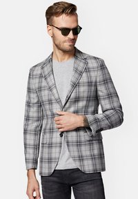 Szary marynarka w kratkę o dopasowanym kroju, z kontrastowymi czarnymi guzikami, klapami na notch oraz gładką teksturą, połączona z szarym T-shirtem.