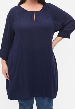Blusa tunica blu navy con scollatura rotonda e dettaglio a chiave, con maniche a tre quarti con texture arricciata. Tessuto morbido.
