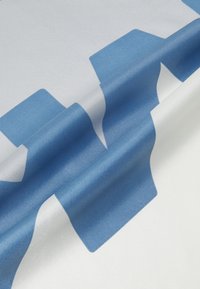 Stof med store blå geometriske former på en hvid baggrund. Glat tekstur med en let glans, der fremhæver de dristige designelementer.
