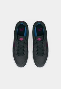 Nike SB batai pasižymi tamsiai pilku zomšu, rožiniais akcentais ir mėlynai juodu vidumi. Plokščios raištelės ir baltas gumos padas užbaigia dizainą.