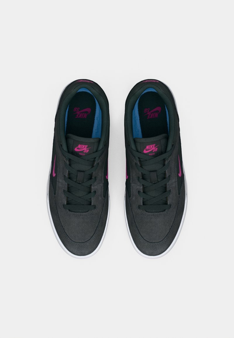 Las zapatillas Nike SB presentan una parte superior de ante gris oscuro, acentos en rosa y un interior en azul y negro. Los cordones planos y una suela de goma blanca completan el diseño.
