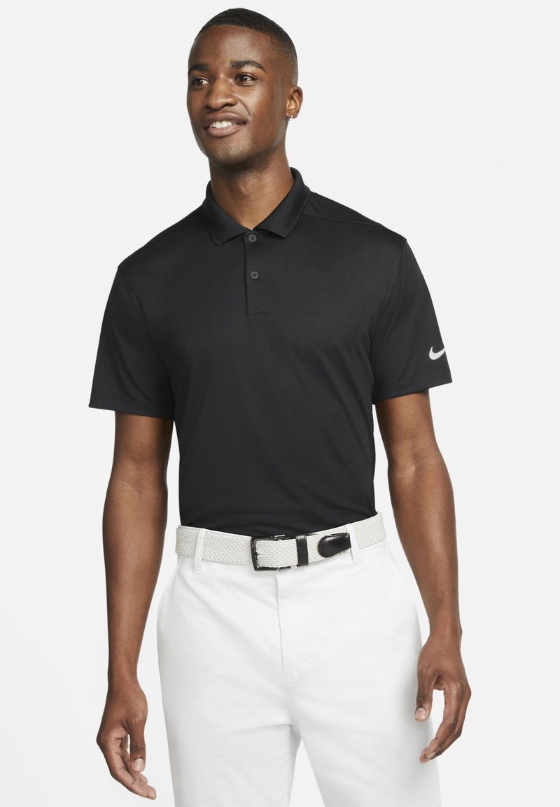 Czarna koszulka polo z trzema guzikami, krótkimi rękawami i białym logo Nike. W połączeniu z białymi spodniami i fakturowanym paskiem.
