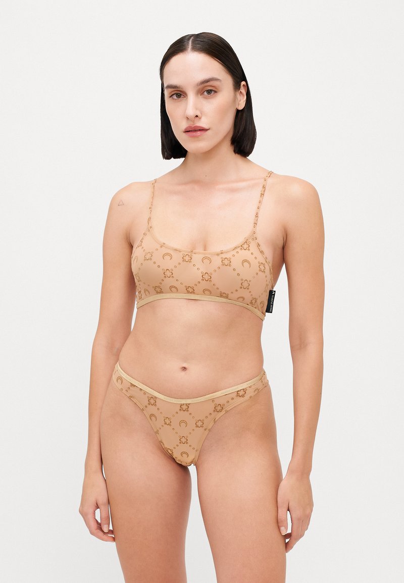 Nude bikini set made of stretch fabric with a patterned design featuring circular motifs; includes a bralette and high-cut bottoms.