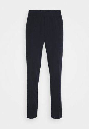Pantalones negros de corte slim fit con cinturilla elástica. Fabricados en tejido suave, presentan un diseño sencillo y perneras rectas. Sin patrones visibles.