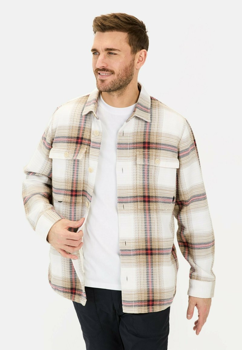 Karierte Hemd mit einem Muster aus Weiß, Beige und Braun, versehen mit roten Akzenten, kragenförmigem Design und Brusttaschen. Getragen über einem weißen T-Shirt.