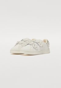 Zapatillas blancas con acentos florales, cuero texturizado, puntera redondeada y perfil bajo, que cuentan con cordones y un interior acolchado.