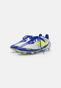 Scarpe da calcio con tomaia in sintetico grigia e blu, caratterizzate da un motivo a zigzag e dettagli in neon giallo. I lacci sono blu; i tacchetti sono traslucidi.