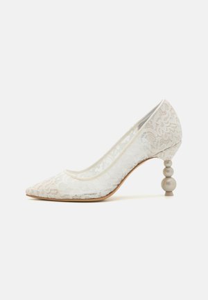 Lace pointed-toe pump in white with a transparent base. Features a unique rounded bead-like heel in gray. Smooth surface and elegant design.