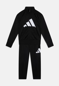Survêtement noir en matériau léger, comprenant une veste zippée avec le logo Adidas blanc et un pantalon assorti avec un placement de logo similaire.