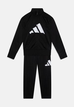 Černý teplákový komplet vyrobený z lehkého materiálu, obsahující zipovou bundu s bílým logem Adidas a odpovídající kalhoty se stejným umístěním loga.