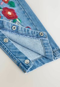 Denimstoff mit mehrfarbiger Blumenstickerei in Rot, Pink und Grün. Verfügt über metallische Druckknöpfe entlang der Kanten.