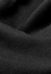Tissu tissé noir avec une surface texturée, affichant des variations subtiles dans la densité du tissage. Drapeau lisse sans motifs ni accents visibles.