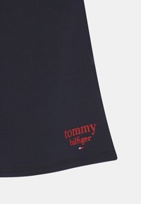 T-shirt in cotone blu navy con maniche corte, caratterizzato dal logo "tommy hilfiger" ricamato in rosso sull'orlo. Texture liscia, vestibilità classica.