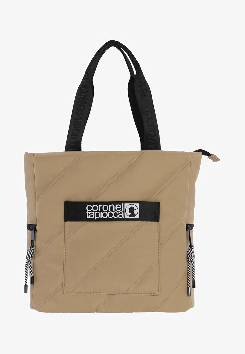 Bolso tote acolchado beige con herrajes negros, que cuenta con un bolsillo frontal con cremallera y un parche con el logotipo, además de asas texturizadas con la marca.