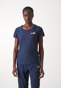 Camiseta deportiva de color marino con mangas cortas, acentos rojos, cuello redondo y un pequeño logo en el lado izquierdo del pecho. Tela suave y transpirable.