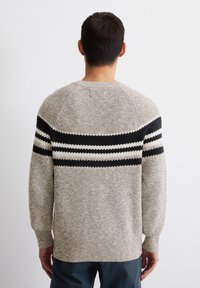 Hellbeige gestrickter Pullover mit schwarz-weißen horizontalen Streifen im oberen Rückenbereich. Verfügt über einen gerippten Kragen und Bündchen.