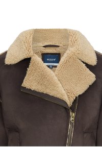 Giacca in shearling marrone con colletto beige morbido e chiusura con zip. Presenta una texture in suede morbido e dettagli con zip color oro.