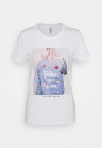 Camiseta de algodón blanca con un gráfico de una mujer con una chaqueta de mezclilla, parches y el texto "Sigue tus sueños" en letras rosas.