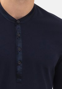 Camicia a maniche lunghe blu navy con colletto arrotondato e tessuto liscio. Presenta una fila di bottoni con cinque bottoni scuri.