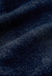 Tamsiai mėlynas tekstūruotas audinys su subtiliais atspalvių pokyčiais, turintis kiek šiurkštų ir audinį primenantį išvaizdą, sukuriantis švelnias bangas.