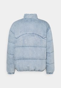 Veste en denim rembourrée de couleur bleu clair avec un col haut, des poignets élastiques et un ourlet froncé. Présente des coutures horizontales pour un toucher supplémentaire.